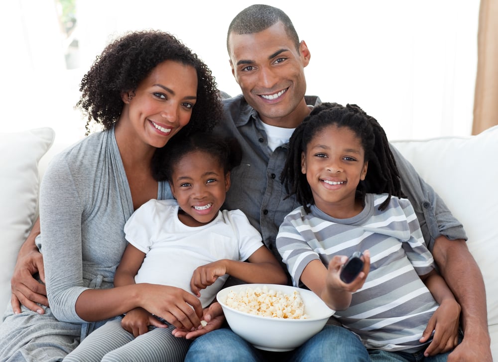 Afro-American family watching television and eating popcorn at home